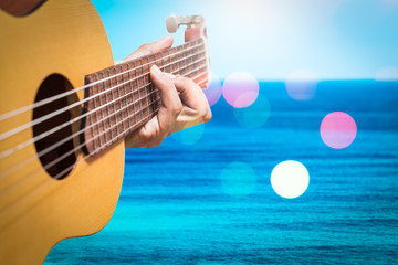 acoustic guitar player on blue sea & colorful bokeh background