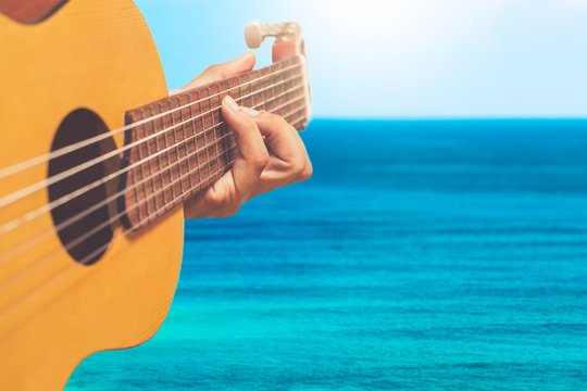 acoustic guitar player on blue sea & skyline background