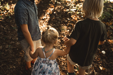 Three children holding hands in woodland 