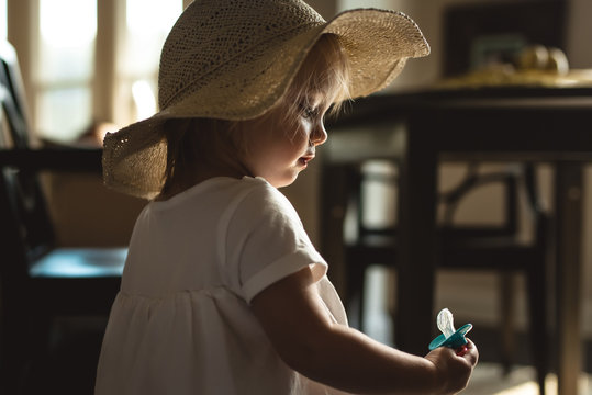 Young girl wearing sun hat staring at dummy 
