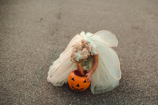Young girl wearing fairy costume and artificial pumpkin 