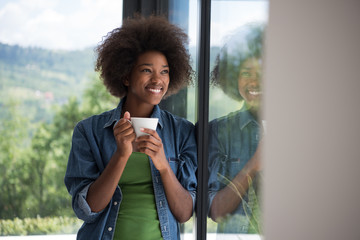 African American woman drinking coffee looking out the window