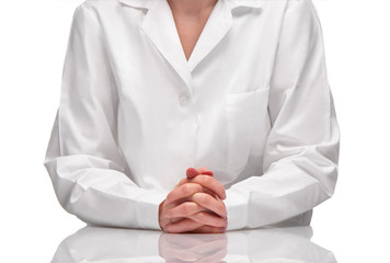 Female in white gown sitting at table against white