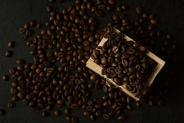 Coffee beans in wooden drawer on dark wooden background. Close up. Selective focus