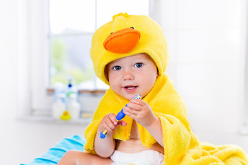 Baby in bath towel with tooth brush