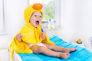 Baby in bath towel with tooth brush