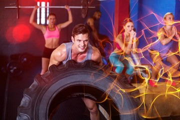 Obraz na płótnie Canvas Smiling man lifting tire in gym