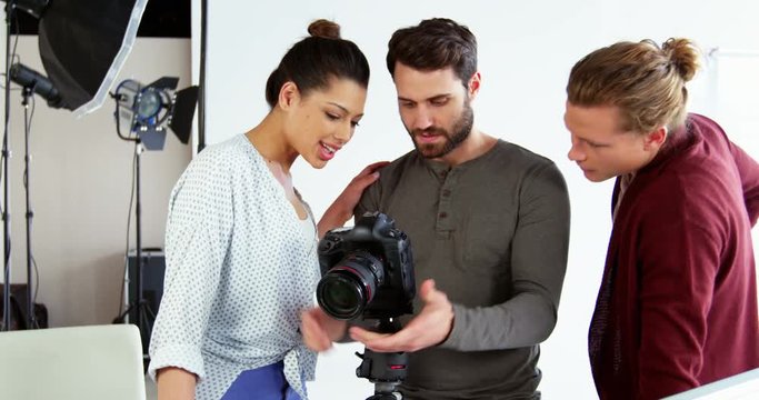 Photographer showing photos to fashion model during photo-shoot in studio 4k