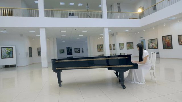 Graceful woman pianist playing piano in opera hall. 4K.