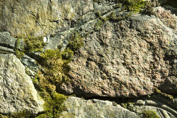Old stonework covered with moss, stone wall reliability, village
