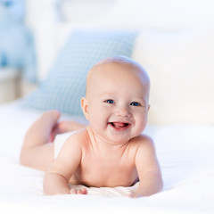Baby in diaper in bed. Newborn at home.