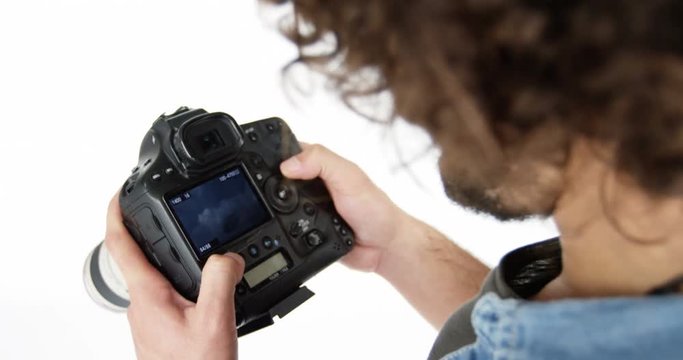 Photographer looking at photos on digital camera in studio 4k