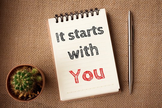 It starts with you, Text message on brown Notebook / business concept