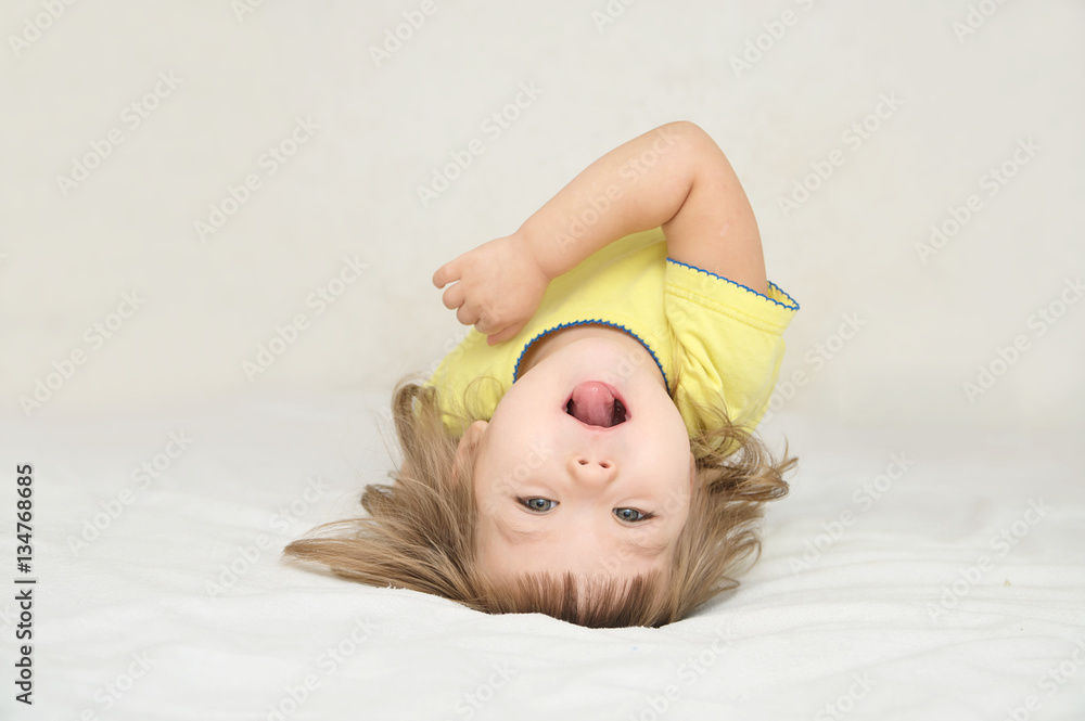 Wall mural Little girl having fun lying on back spine, back bend, bridge figure, happy smiling child, happiness childhood concept