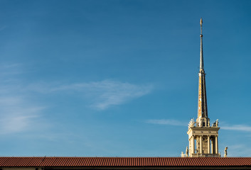 Fragment of the Sochi port building, spire and part of the roof on blue sky background.