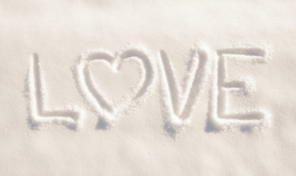 Word love  with a heart, written in fresh powdery snow - concept of loving winter weather