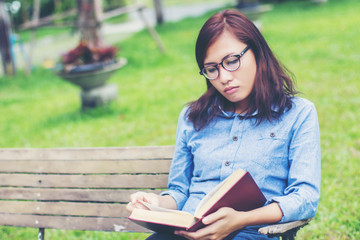 Obraz premium Hipster charming girl relaxing in the park while read book, Enjo