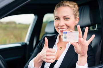 Woman showing driving license and thumbs up - obrazy, fototapety, plakaty