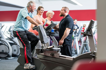 Group spinning with personal trainer in gym