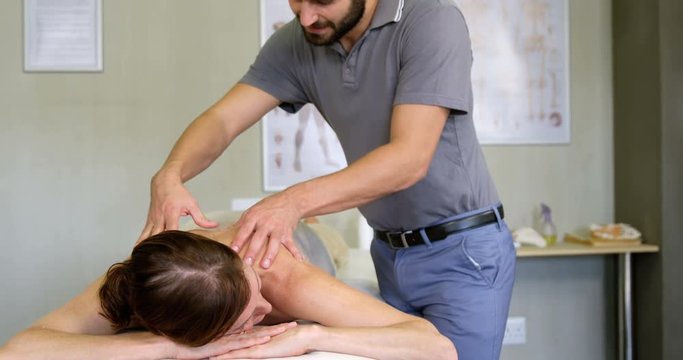 Physiotherapist giving back massage to a woman in clinic 4k