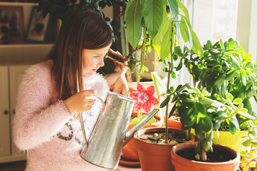 Little girl watering home plants in pots