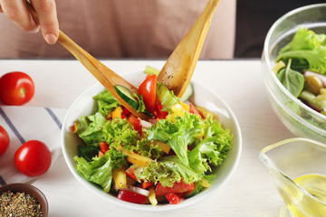 Woman cooking tasty vegetable salad on kitchen