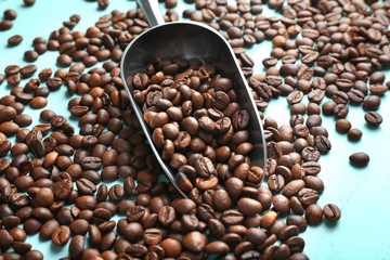 Roasted coffee beans and metal scoop on wooden table closeup