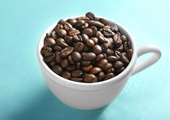 Cup of roasted coffee beans on wooden background