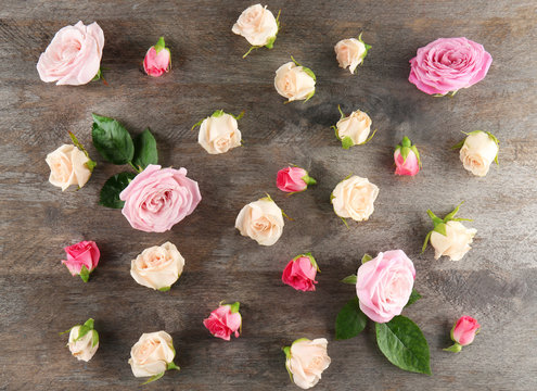 Beautiful roses on wooden background, top view
