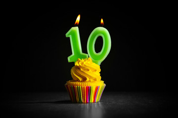 Birthday cupcake with candles on dark background
