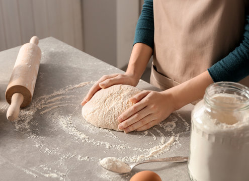 Woman preparing dough on table at kitchen