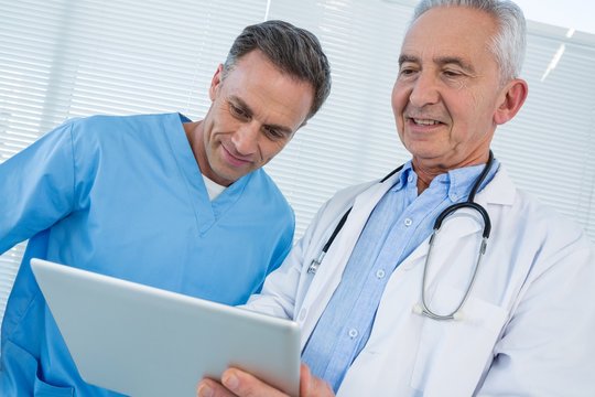 Surgeon and doctor discussing over digital tablet