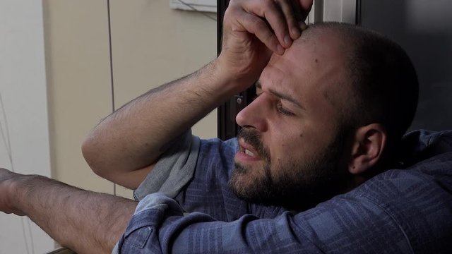  distressed man touching his forehead to the window reflects