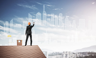 Man architect draw silhouette of modern city on blue sky. Mixed 