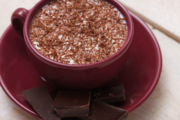 Milk chocolate in a cup on a saucer on a wooden background. Clos