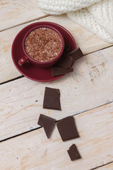 Milk chocolate in a cup on a saucer on a light wooden background