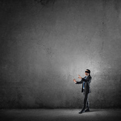 Business concept of risk with businessman wearing blindfold in empty concrete room