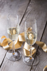 two champagne glasses with gold ribbon on wood board.valentines