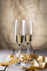 two champagne glasses with gold ribbon on wood board.valentines