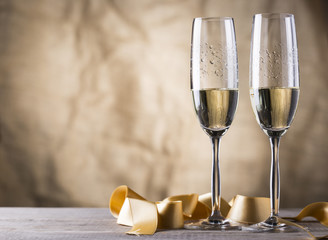 two champagne glasses with gold ribbon on wood board.valentines