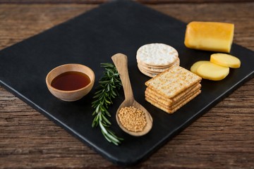 Cheese, crackers, nacho chips and rosemary herbs on slate plate