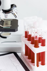 blood in glass tubes on background of microscope