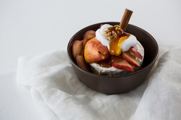 Brie cheese served with fruit slices and walnut in a bowl