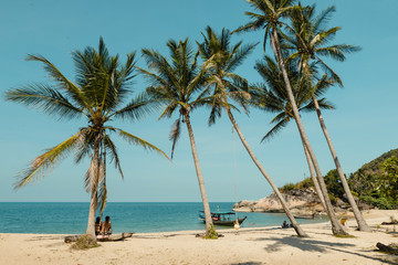 Tourists relaxing on tropical beach with white sand