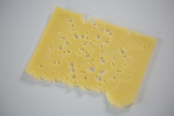 Slice of cheese on white background