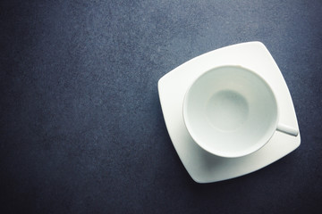 Empty white coffee cup on black empty surface.