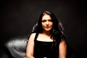Fototapeta premium Young Woman Sitting In A Black Armchair