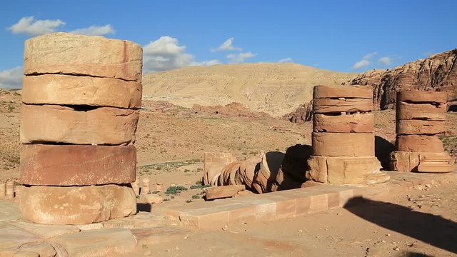Ancient columns of Great Temple or Temple of Winged Lions in Petra - historical and archaeological rock-cut city in Hashemite Kingdom of Jordan. Royal Tombs carved in the mountain on the background