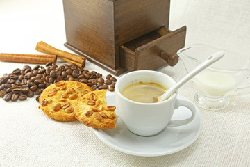 Coffee cup, biscuit, grinder and coffeebeans on table
