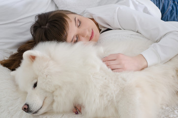 beautiful girl sleeping on a fur rug with snow white Samoyed